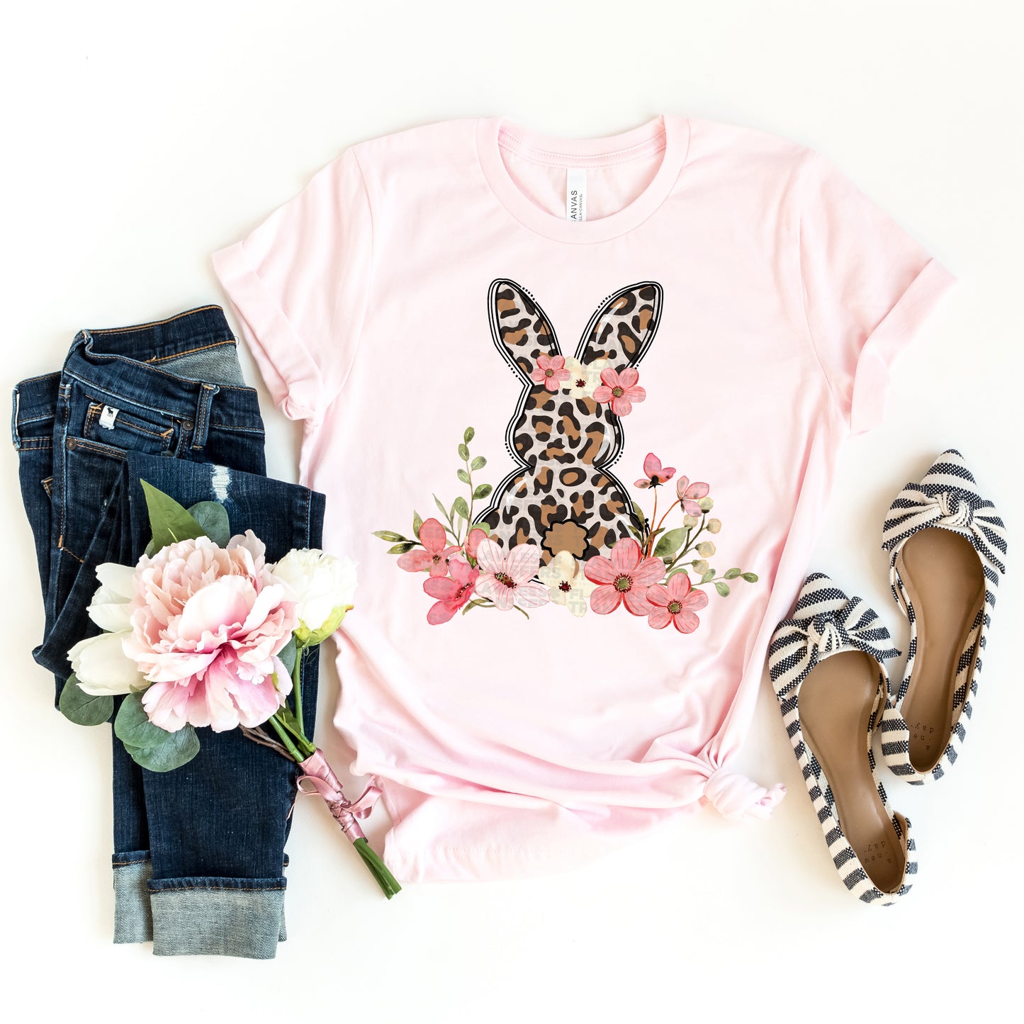 Pink t-shirt with leopard print bunny design, jeans, flats, and flowers on a white background